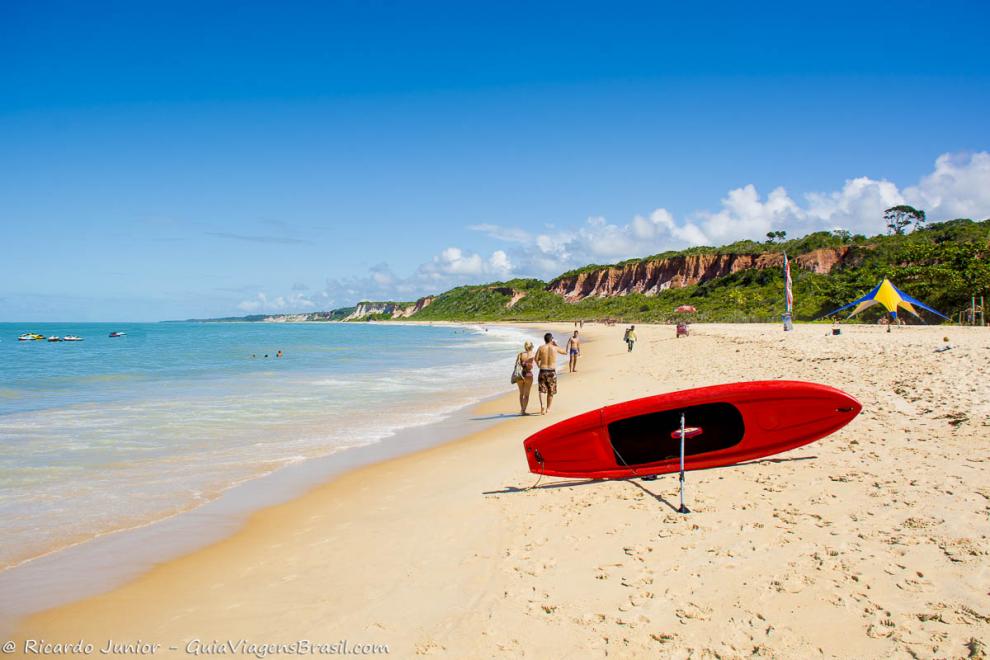 Imagem das pessoas caminhando e caiaque na areia da bela Praia de Pitinga.